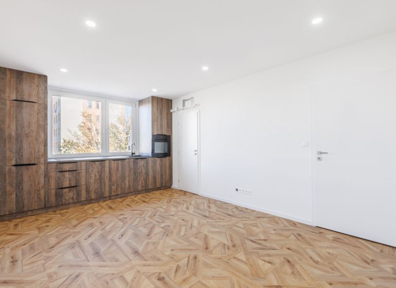 Wohnzimmer in einer 2-Zimmer-Wohnung mit Küchenzeile und Holzboden.