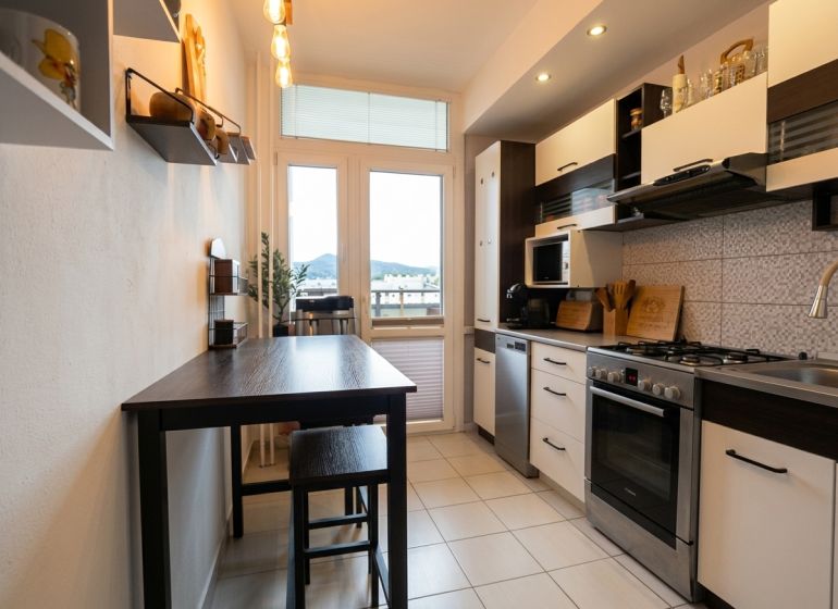 Küche in einer 2-Zimmer-Wohnung mit dunklem Tisch und hellem Boden.