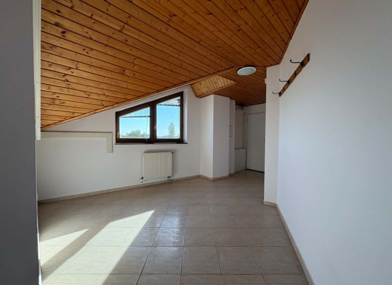 Ein Dachzimmer in einer 3-Zimmer-Wohnung mit einer Holzdecke und Fliesenboden.