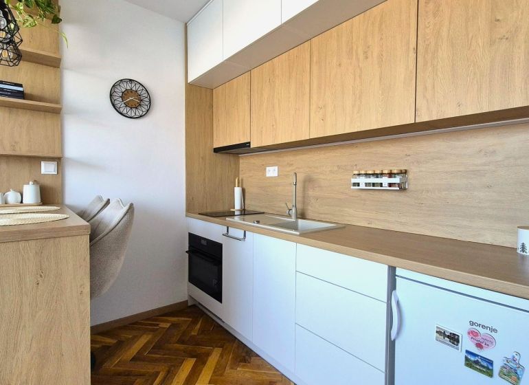 Küchenzeile in einem Einzimmerapartment mit Holzboden und eingebauten Geräten.
