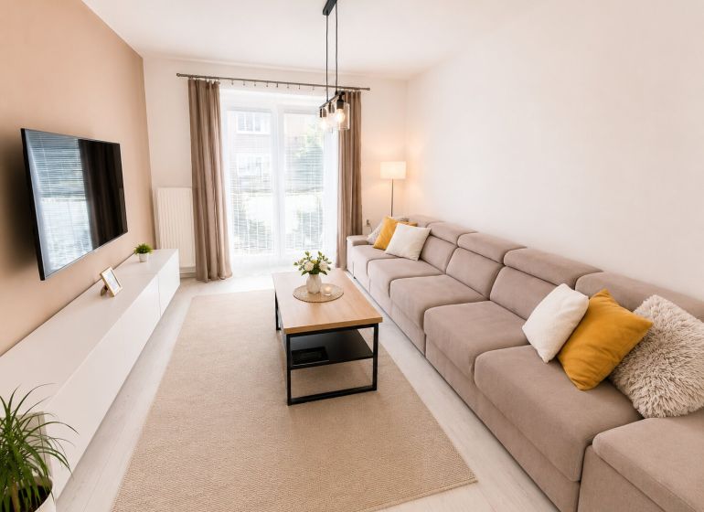 Helles Wohnzimmer in einer 2-Zimmer-Wohnung mit einem bequemen Sofa und Fenstern.