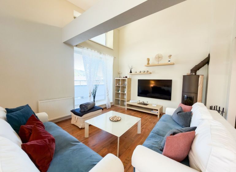 Wohnzimmer in einer 3-Zimmer-Wohnung mit Holzboden, bequeme Sofas, Fernseher.