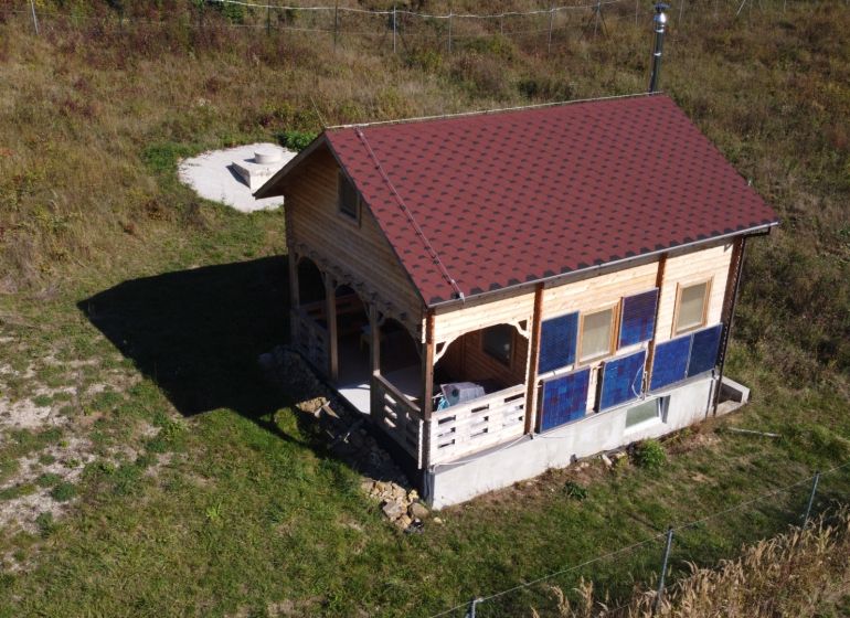 Eine Hütte in Horná Breznica mit Holzverkleidung und rotem Dach auf einem grünen Grundstück.