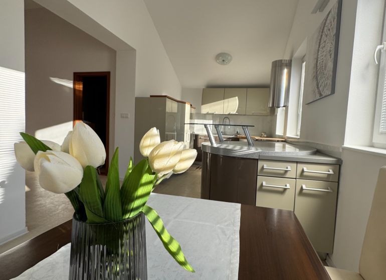 Küche in einem Einfamilienhaus mit einer dekorativen Vase und weißen Blumen auf dem Tisch.