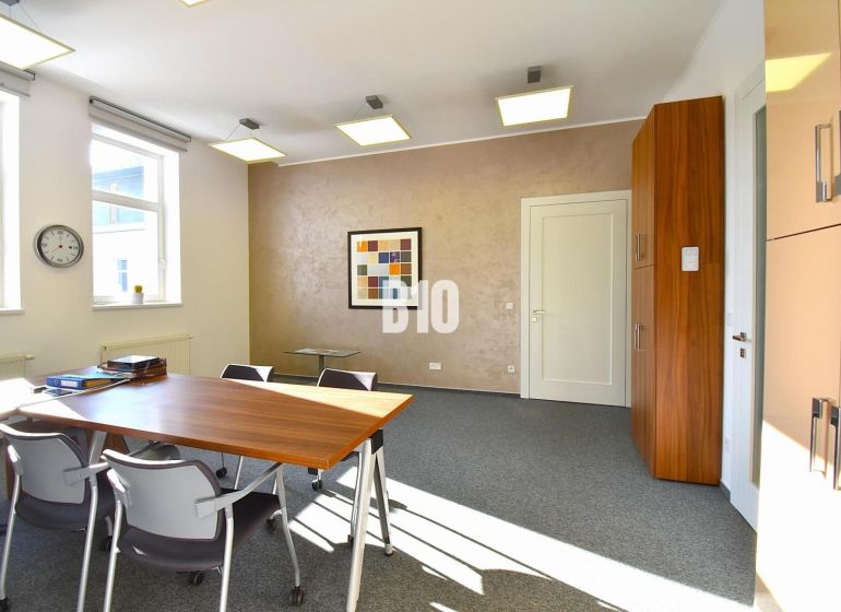 Ein Bürointerieur mit Teppichboden, Tisch, Stühlen und einem Wandbild.