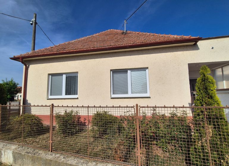 Ein Einfamilienhaus in Ludanice mit weißer Fassade und rotem Dach, eingezäunter Garten.