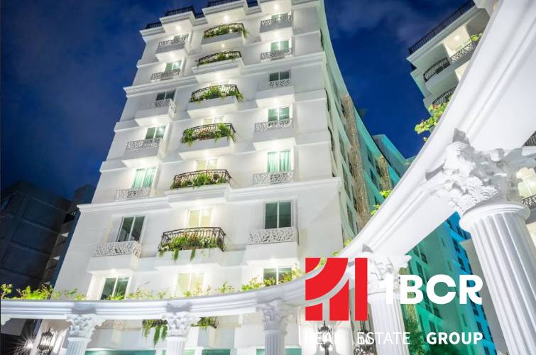 Ein im Bau befindliches Wohngebäude in Pattaya mit weißer Fassade und Balkonen mit Pflanzen.