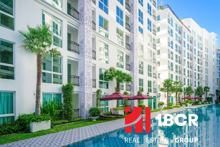 Wohnungsbau in Pattaya: Weißer Wohnkomplex mit Palmen und Pool.