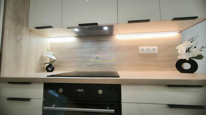 Küchenzeile in einem Einzimmerapartment mit Holzdekor und modernen Küchengeräten.