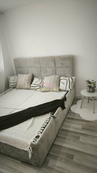 Einzimmerwohnung mit Bett und Nachttisch auf hellem Boden, geschmackvolle Dekoration.