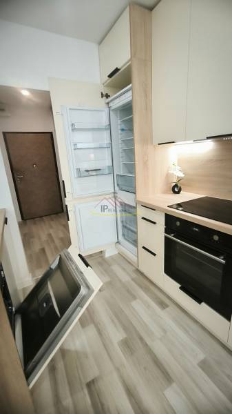 Küche in einem Studio-Apartment mit offenen Geräten und hellem Holz auf dem Boden.