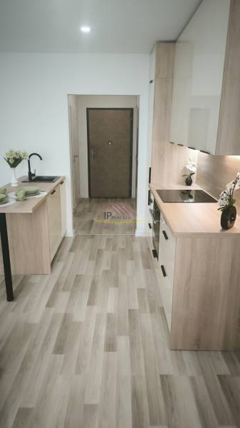 Küche in einem Einzimmerapartment mit Holzboden, Herd und Esstisch.