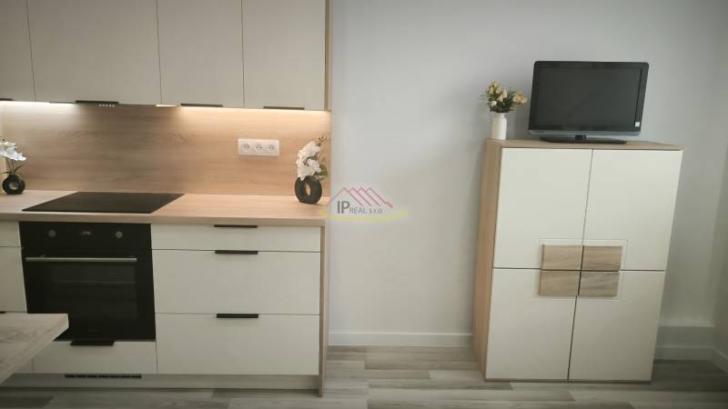 Küchenzeile und Schrank mit Fernseher in einem Einzimmerapartment.