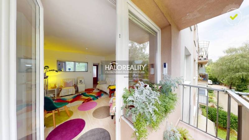 Ein Balkon mit Blick ins Grüne, Eingang in eine helle 4-Zimmer-Wohnung mit farbenfrohem Interieur.