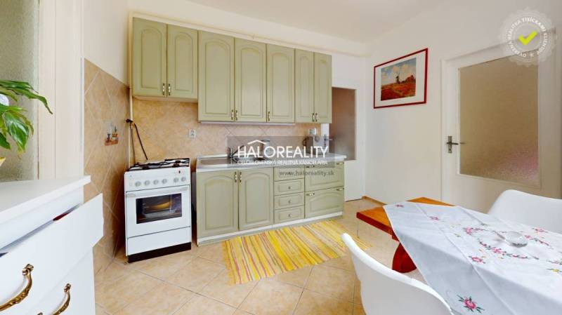 Küche einer 4-Zimmer-Wohnung mit hellen Schränken, Esstisch und Backofen.