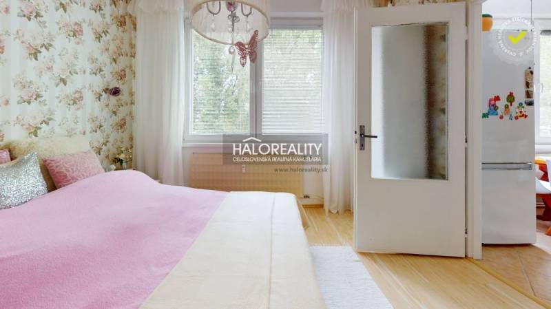 Schlafzimmer in einer 4-Zimmer-Wohnung mit Blumen-Tapete, Bett und Kronleuchter.