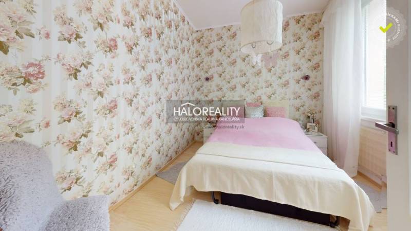 Schlafzimmer in einer 4-Zimmer-Wohnung mit Blumen-Tapeten und Bett.