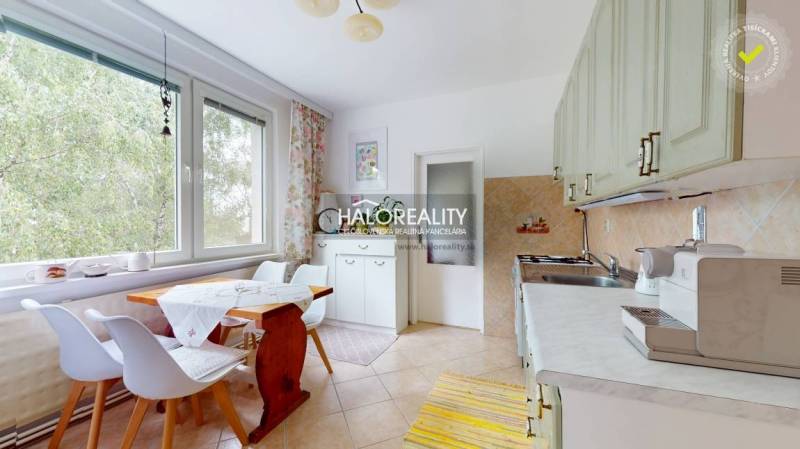 Küche in einer 4-Zimmer-Wohnung mit Holztisch, Stühlen und einem großen Fenster mit Vorhang.