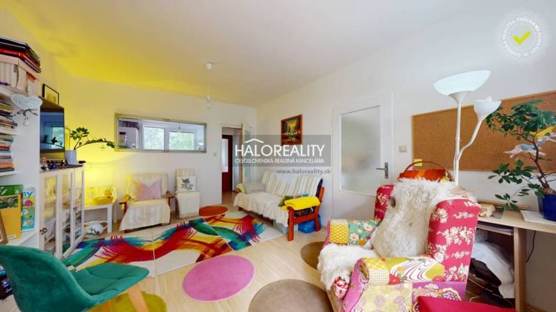 Ein farbenfrohes Wohnzimmer in einer 4-Zimmer-Wohnung mit verschiedenen gemusterten Sesseln und Dekorationen.