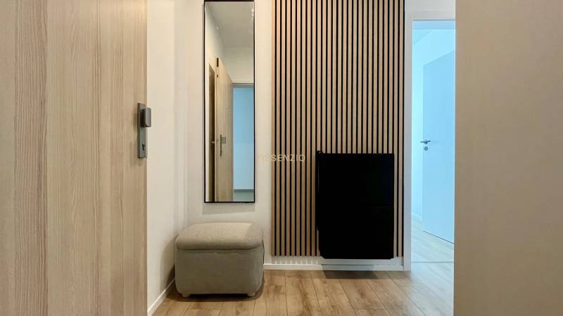 Flur mit Holzverkleidung und Spiegel in einer 2-Zimmer-Wohnung.