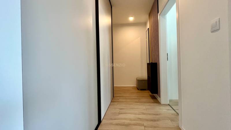 Der Flur in einer 2-Zimmer-Wohnung mit hellen Holzböden und weißen Wänden.