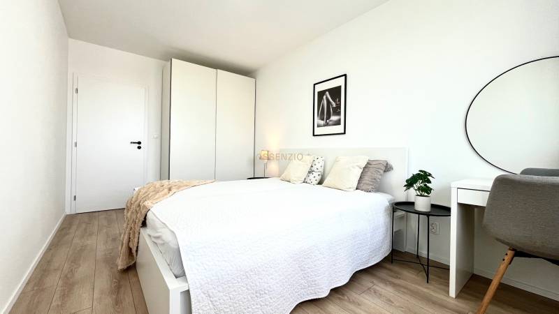 Helles Schlafzimmer mit Bett, Kleiderschrank, Schreibtisch in einer 2-Zimmer-Wohnung.