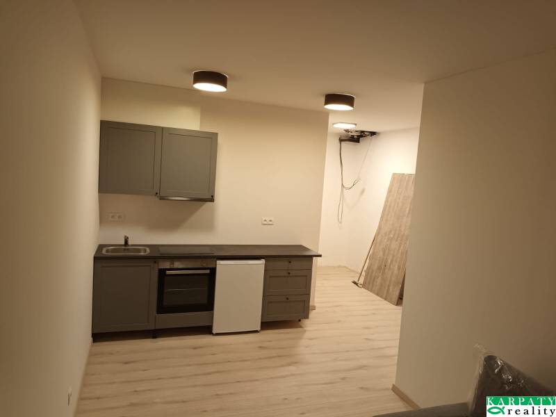 Küchenzeile in einer Einzimmerwohnung mit Bodenbelag und hellem Möbel.