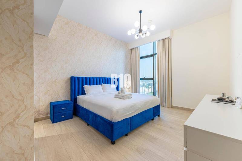 Schlafzimmer in einer 3-Zimmer-Wohnung mit blauem Bett, Kommode und moderner Beleuchtung.