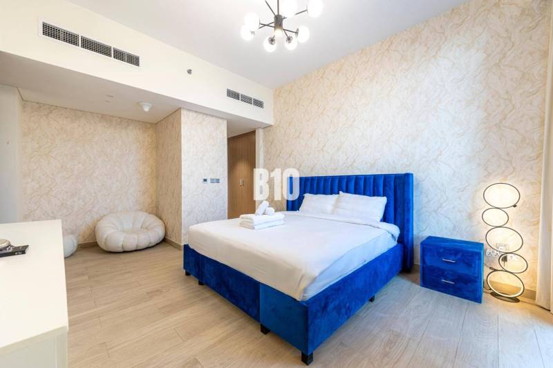 Schlafzimmer mit blauem Bett und sanft gemusterten Wänden in einer 3-Zimmer-Wohnung.