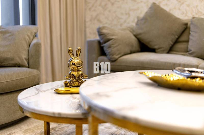 Goldene Hasenstatue auf einem Marmortisch in einer 3-Zimmer-Wohnung mit einem bequemen grauen Sofa.