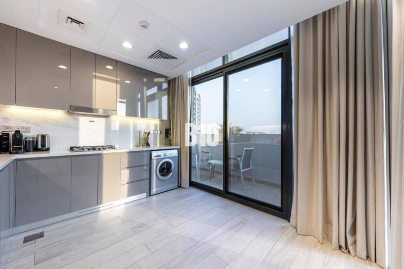 Küche in einer 3-Zimmer-Wohnung mit Waschmaschine und Balkon, helle Schränke, großes Fenster.