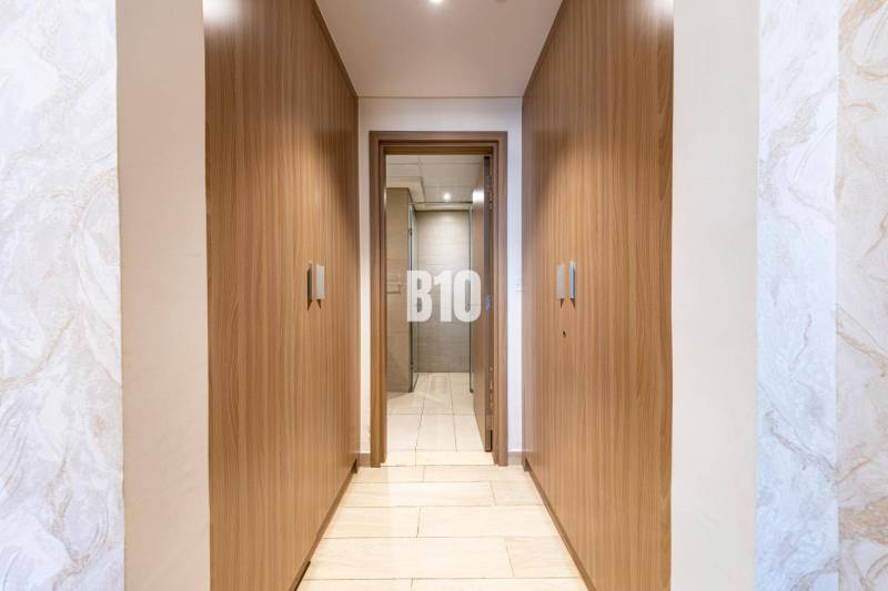 Ein enger Flur mit eingebauten Holzschränken und Blick ins Badezimmer in einer 3-Zimmer-Wohnung.