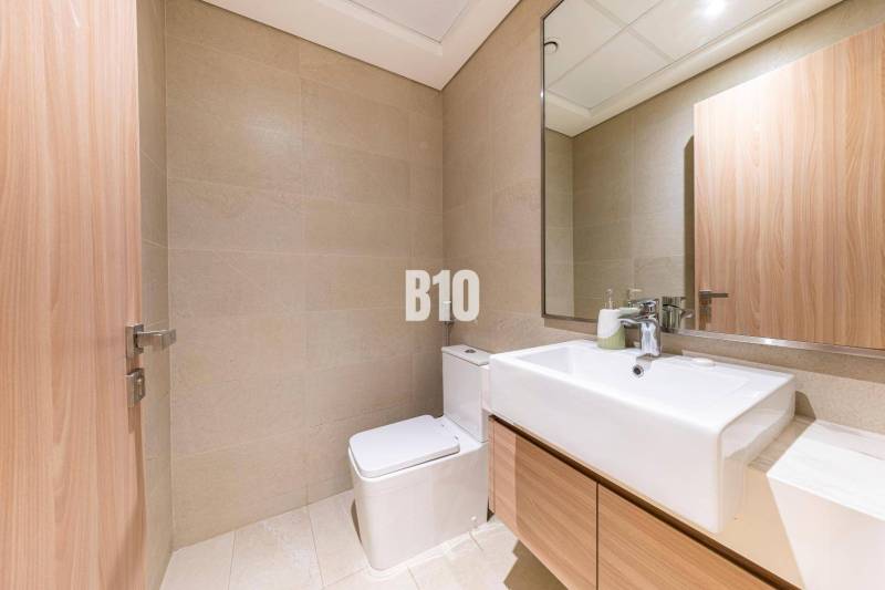 Badezimmer in einer 3-Zimmer-Wohnung mit hellen Fliesen, Spiegel und Waschbecken.