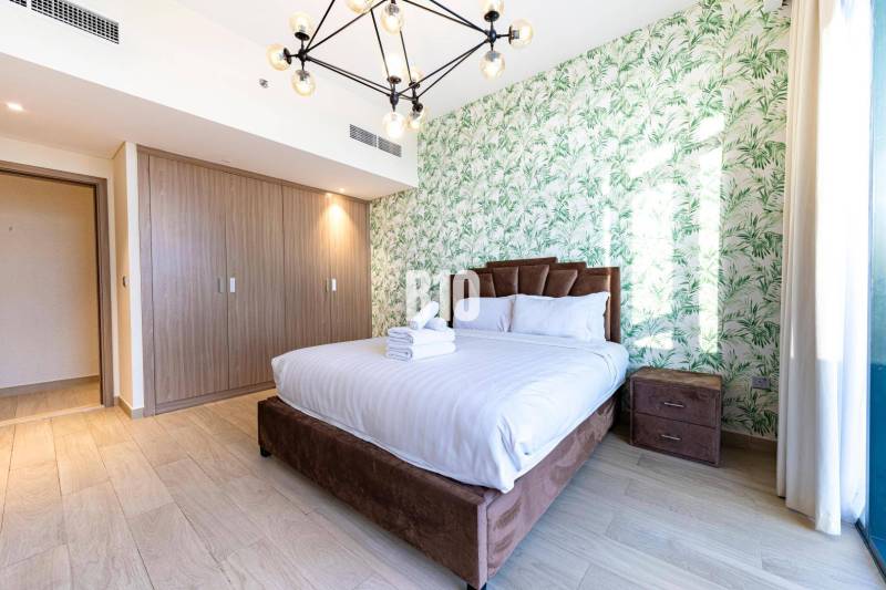 Schönes Schlafzimmer in einer 3-Zimmer-Wohnung mit Bett, botanischer Tapete und Holzschrank.