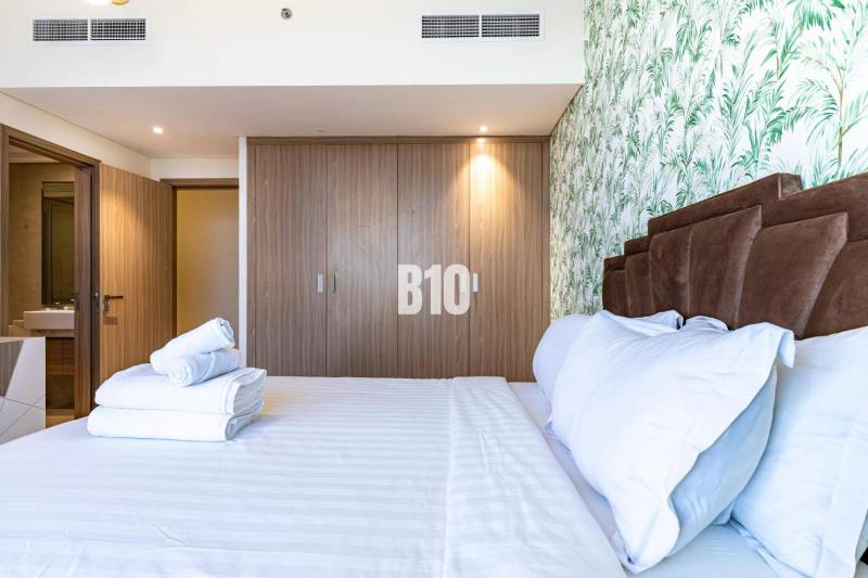 Schlafzimmer mit Doppelbett, Holzschrank und geblümter Tapete in einer 3-Zimmer-Wohnung.