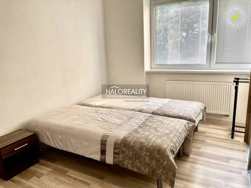 Schlafzimmer in einer 3-Zimmer-Wohnung mit zwei Betten, einem Nachttisch und einem großen Fenster.