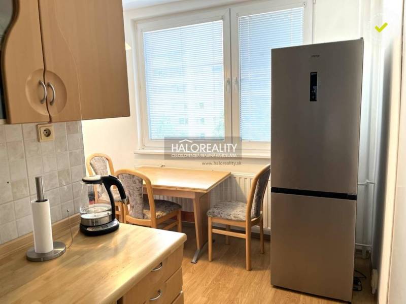 Küche in einer 3-Zimmer-Wohnung mit Kühlschrank, Holztisch und Sesseln.