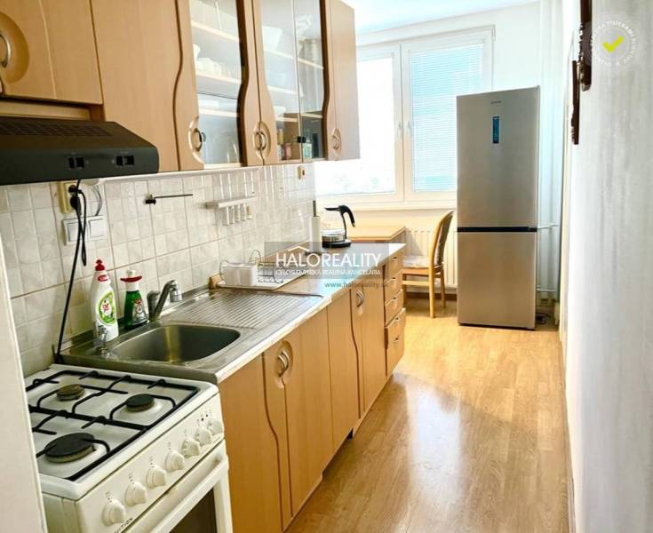 Küche mit Gasherd und Kühlschrank in einer 3-Zimmer-Wohnung, helle Arbeitsplatte.