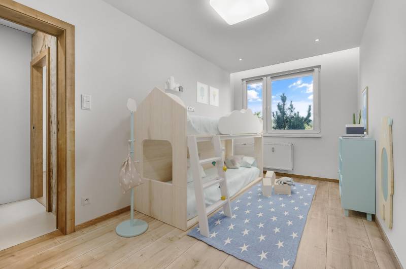 Kinderzimmer in einer 4-Zimmer-Wohnung mit einem Etagenbett und einem blauen Teppich mit Sternen.