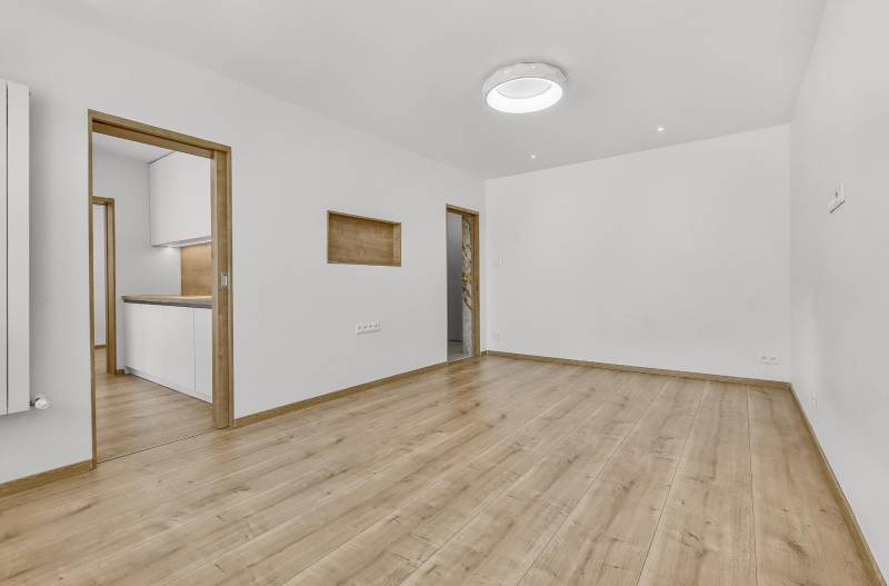 Geräumiges Wohnzimmer mit Holzboden und Zugang zur Küche in einer 4-Zimmer-Wohnung.