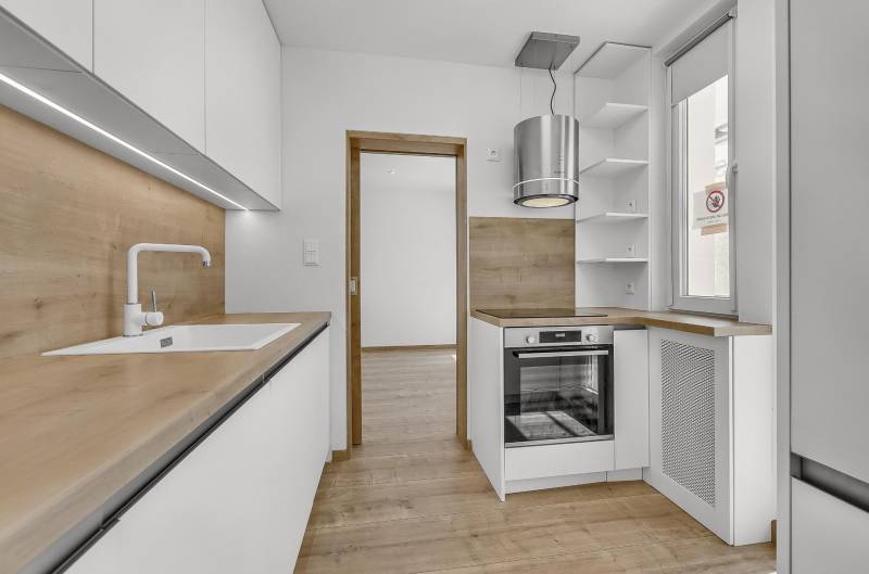 Küche mit Holzelementen und eingebauten Geräten in einer 4-Zimmer-Wohnung.