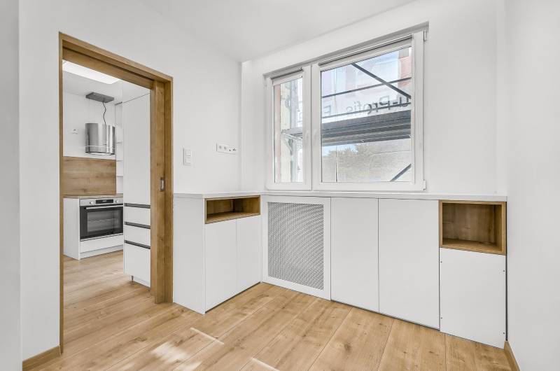Küche einer 4-Zimmer-Wohnung mit Holzboden und weißen Schränken.