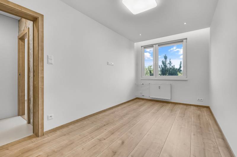 Ein leerer Raum mit Holzboden und Kunststofffenster in einer 4-Zimmer-Wohnung.