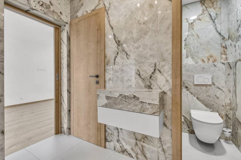 Badezimmer mit hellen Marmorbodenfliesen und eingebautem Hänge-WC in einer 4-Zimmer-Wohnung.