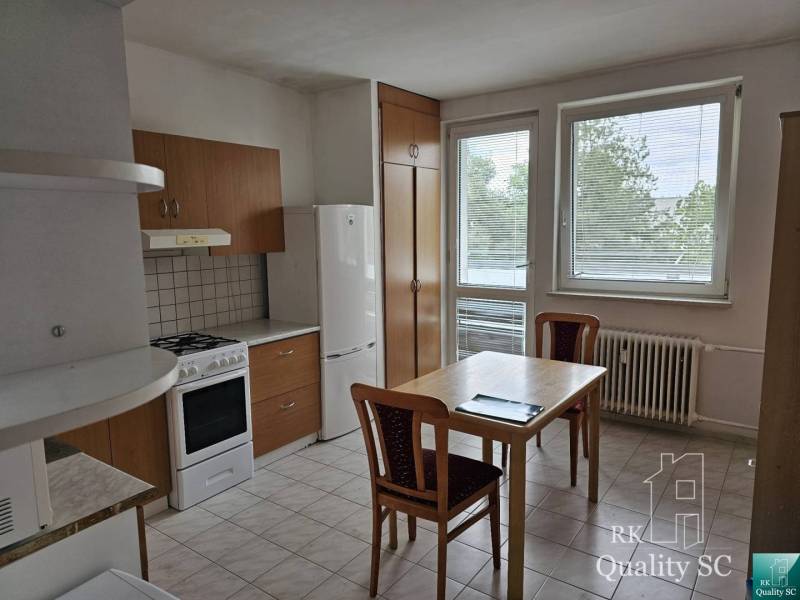Küche in einer 2-Zimmer-Wohnung mit Küchenzeile, Tisch und Stühlen.