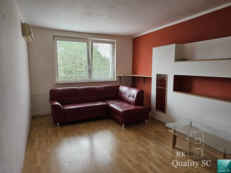 Wohnzimmer mit Ecksofa und Glastisch in einer 2-Zimmer-Wohnung.