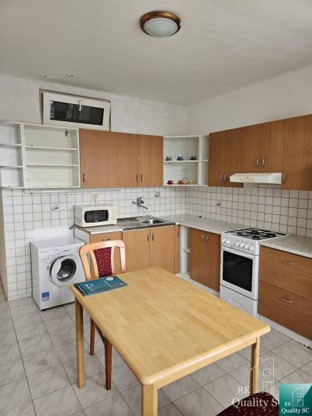 Küche in einer 2-Zimmer-Wohnung mit Küchenzeile, Esstisch und Geräten.