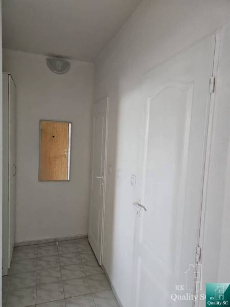 Flur mit Spiegel in einer 2-Zimmer-Wohnung, weiße Wände und Türen, Fliesenboden.