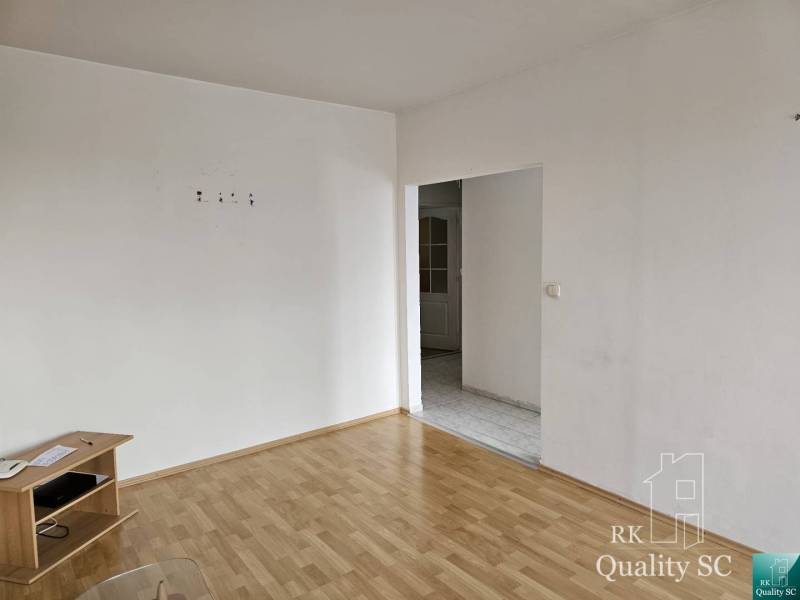 Ein Zimmer in einer 2-Zimmer-Wohnung mit Holzboden und weißen Wänden, mit Möbeln.