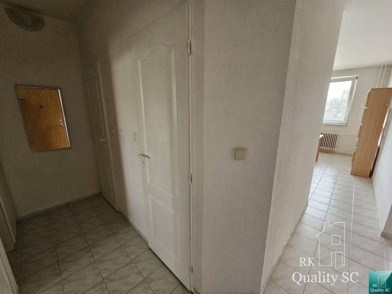 Flur mit hellen Fliesen und weißen Türen in einer Zweizimmerwohnung.